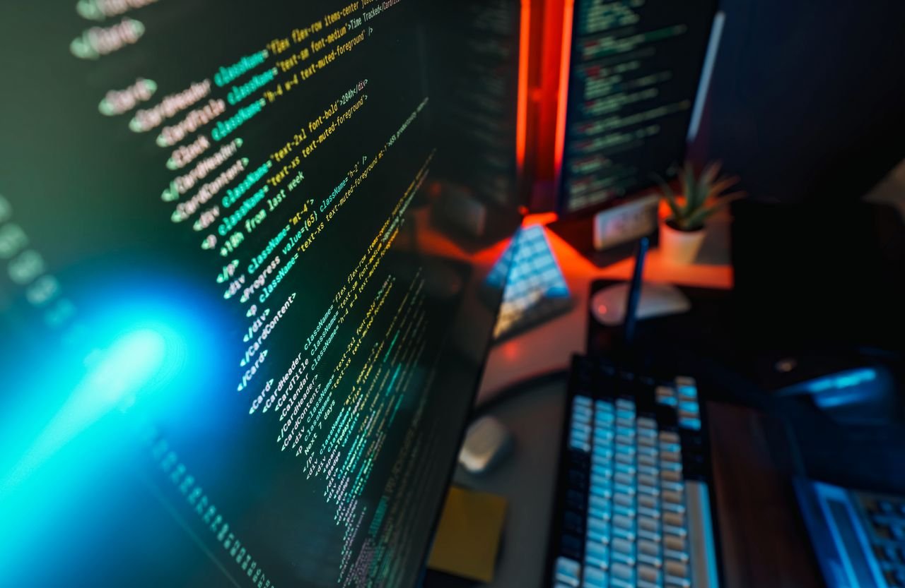 who-we-are Futuristic workspace featuring a glowing computer screen with coding displayed, ideal for technology and programming concepts.